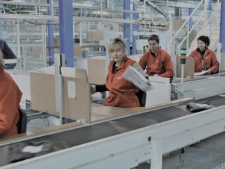 Employés de C-Log qui travaillent sur une chaîne logistique et qui préparent des colis à l'expédition