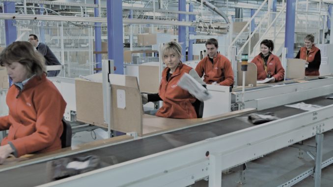 Chaîne logistique Employés de C-Log qui travaillent sur une chaîne logistique et qui préparent des colis à l'expédition