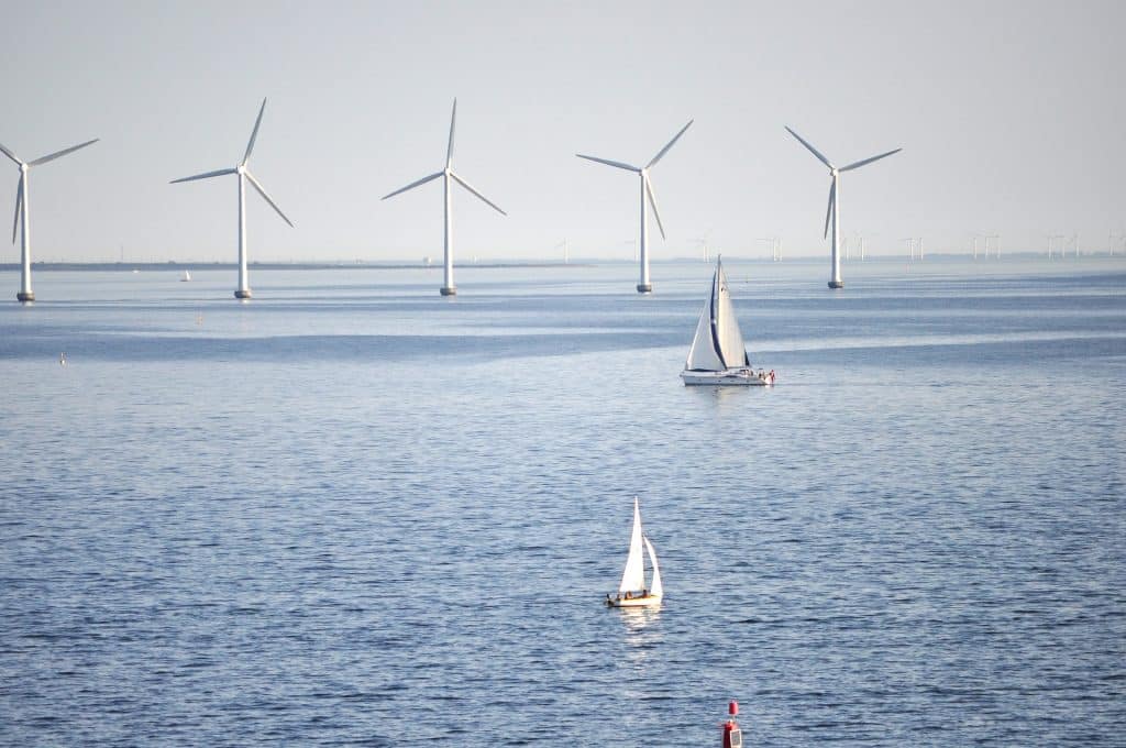 Un parc éolien en mer avec des bateaux de plaisance