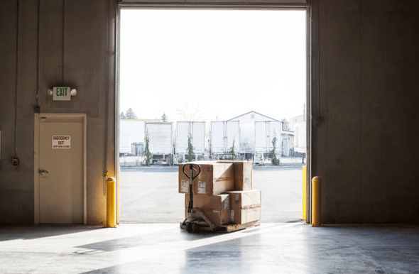 Entrée d'un entrepôt industriel avec un chariot plein de cartons