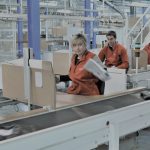 Employés de C-Log qui travaillent sur une chaîne logistique et qui préparent des colis à l'expédition